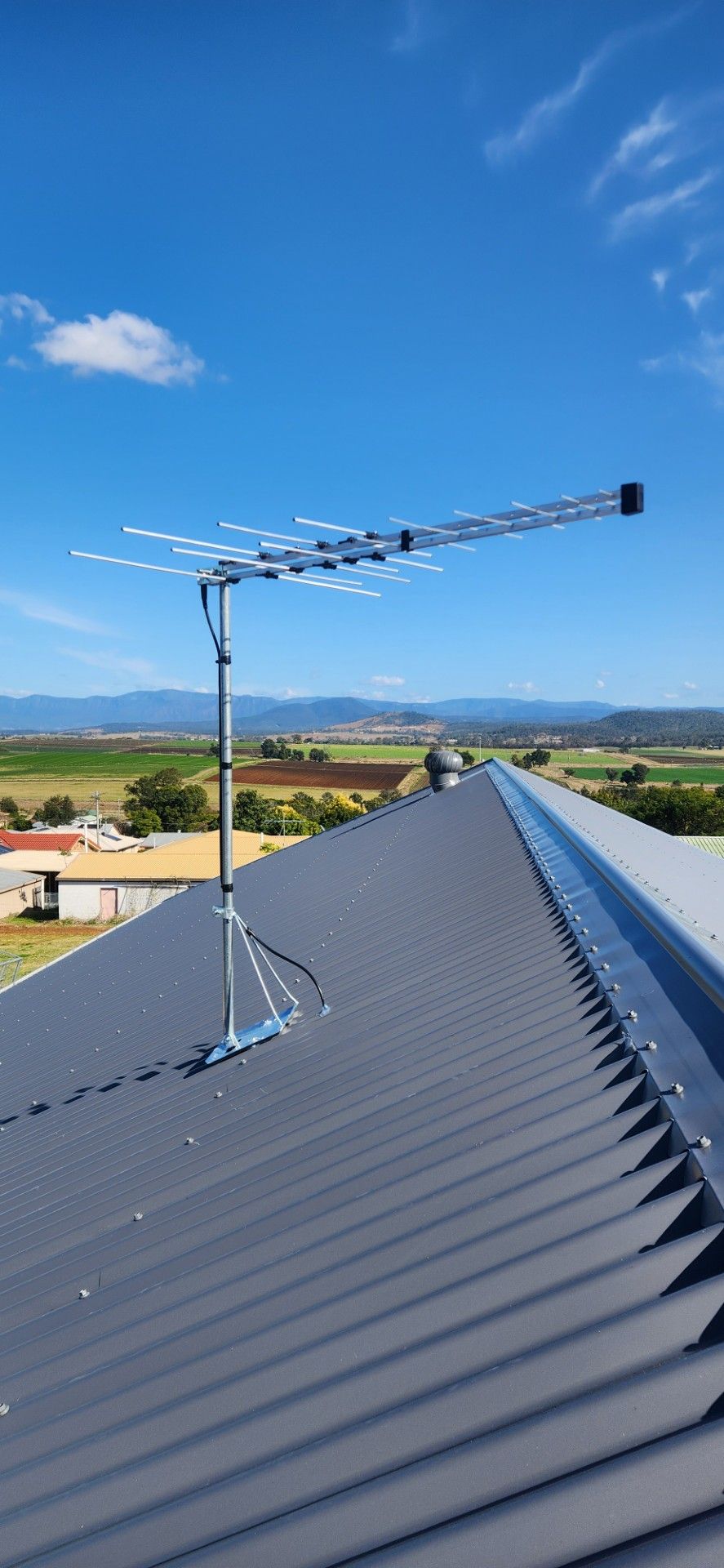 An antenna on top of a tiled roof with a blue sky in the background