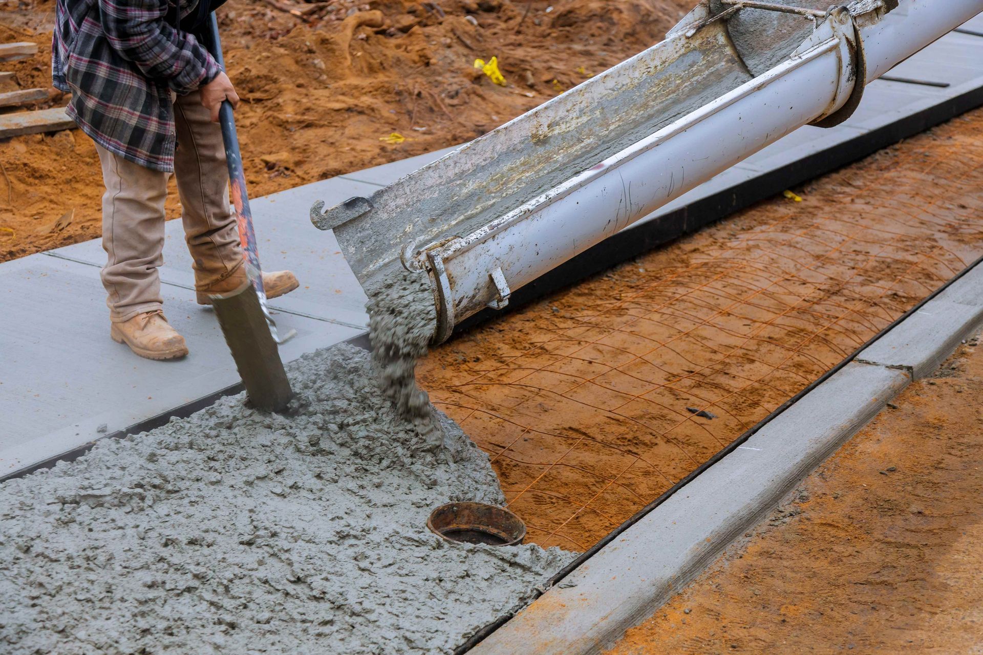 Truck loads of concrete poured into the concrete at a construction in a sidewalk
