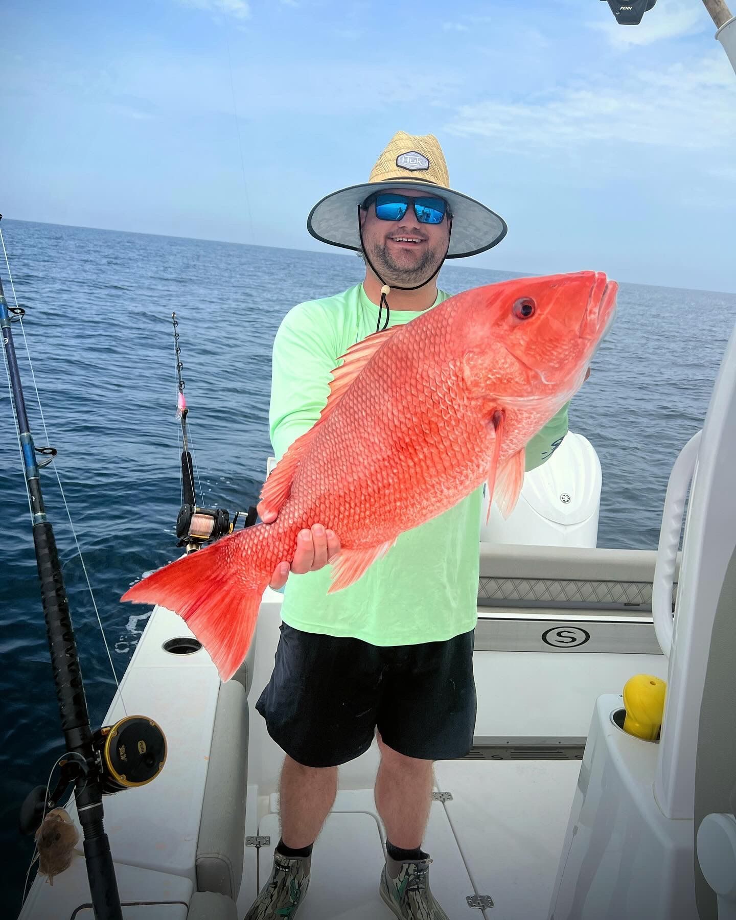 A man is holding a large red fish on a boat.