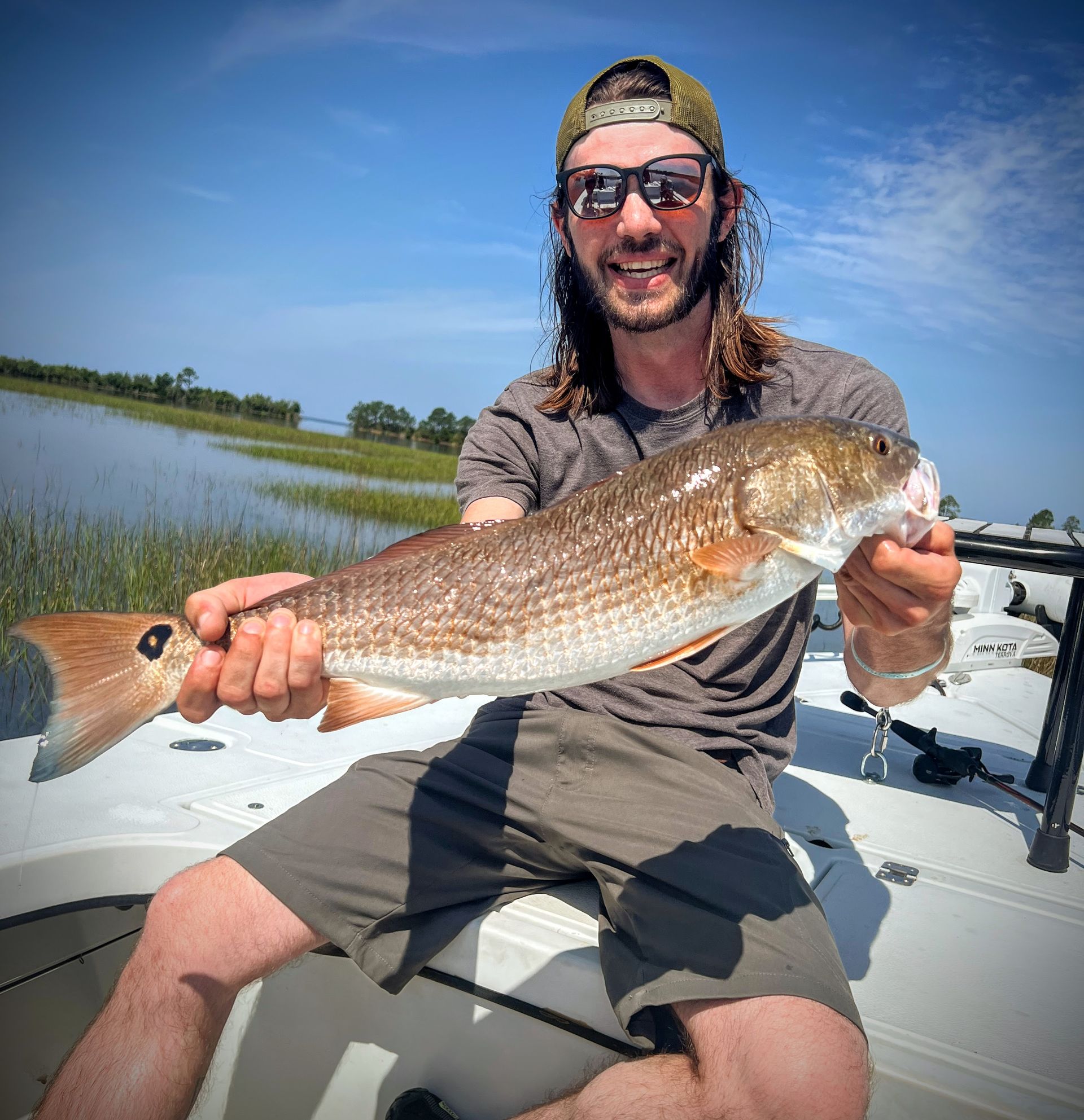 A man is sitting on a boat holding a large fish.