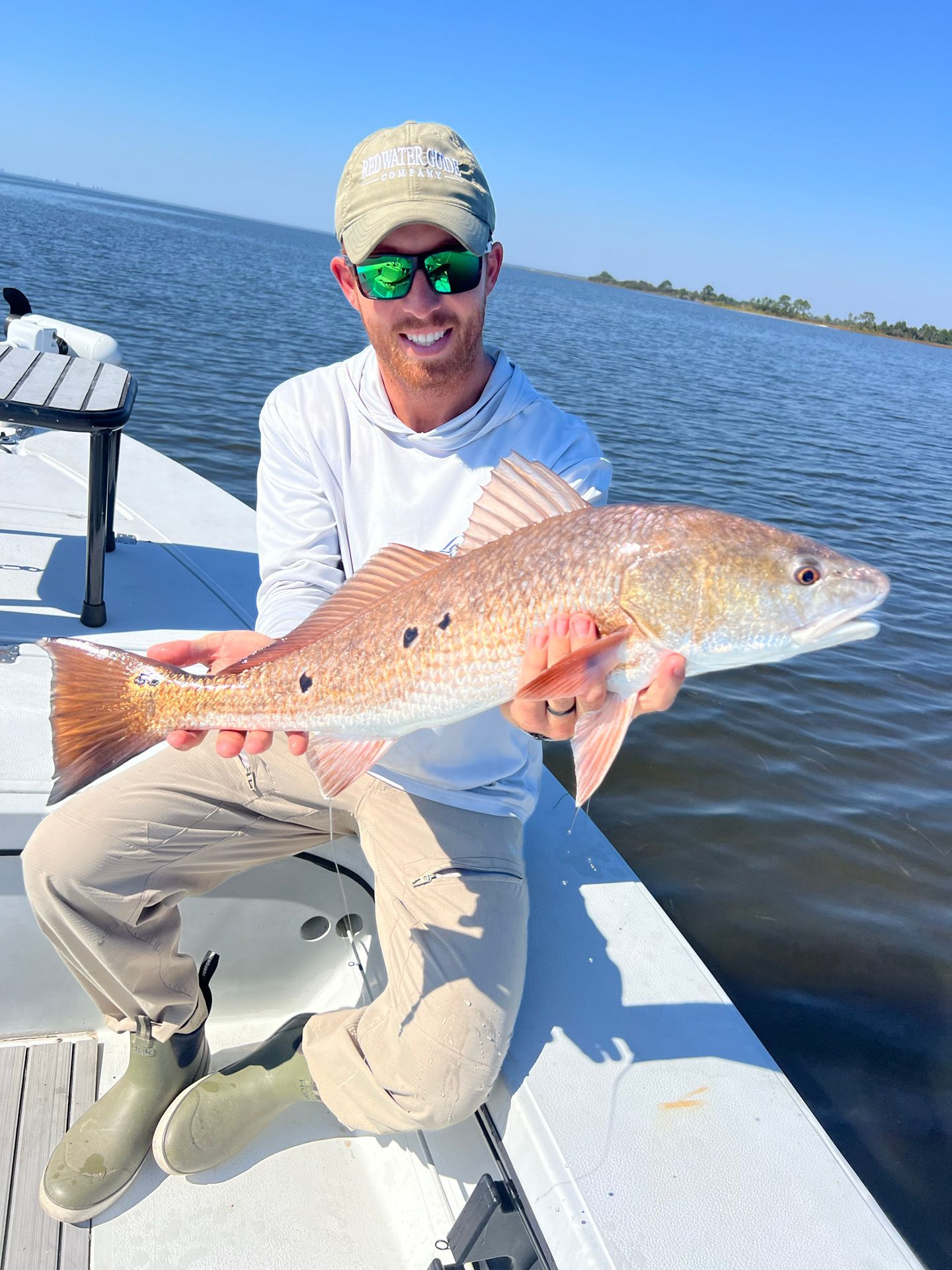 A man is sitting on a boat holding a large red fish.