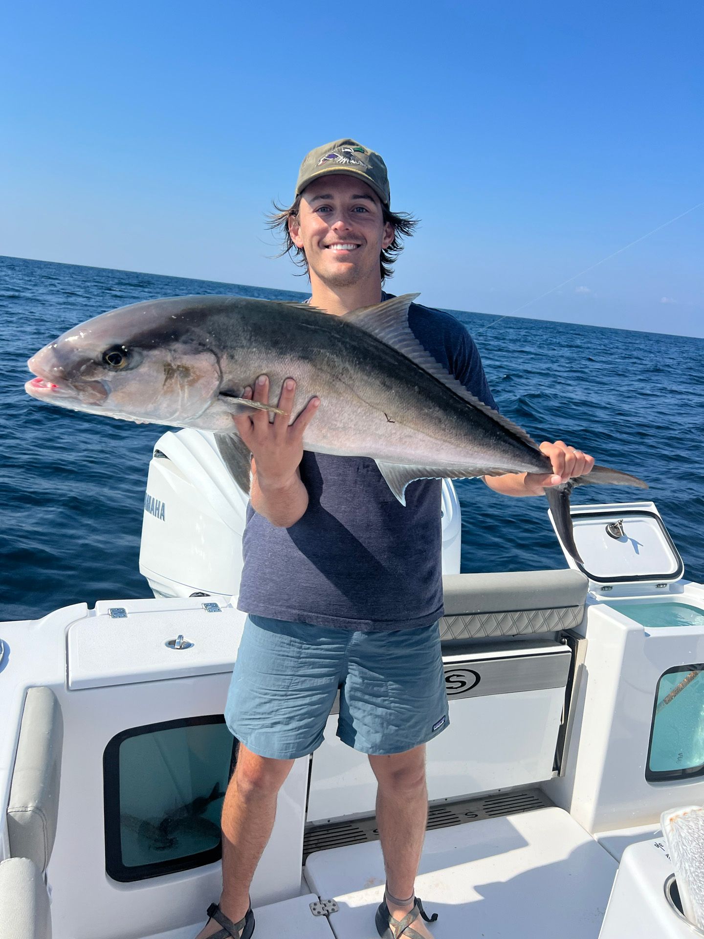 A man is holding a large fish on a boat in the ocean.