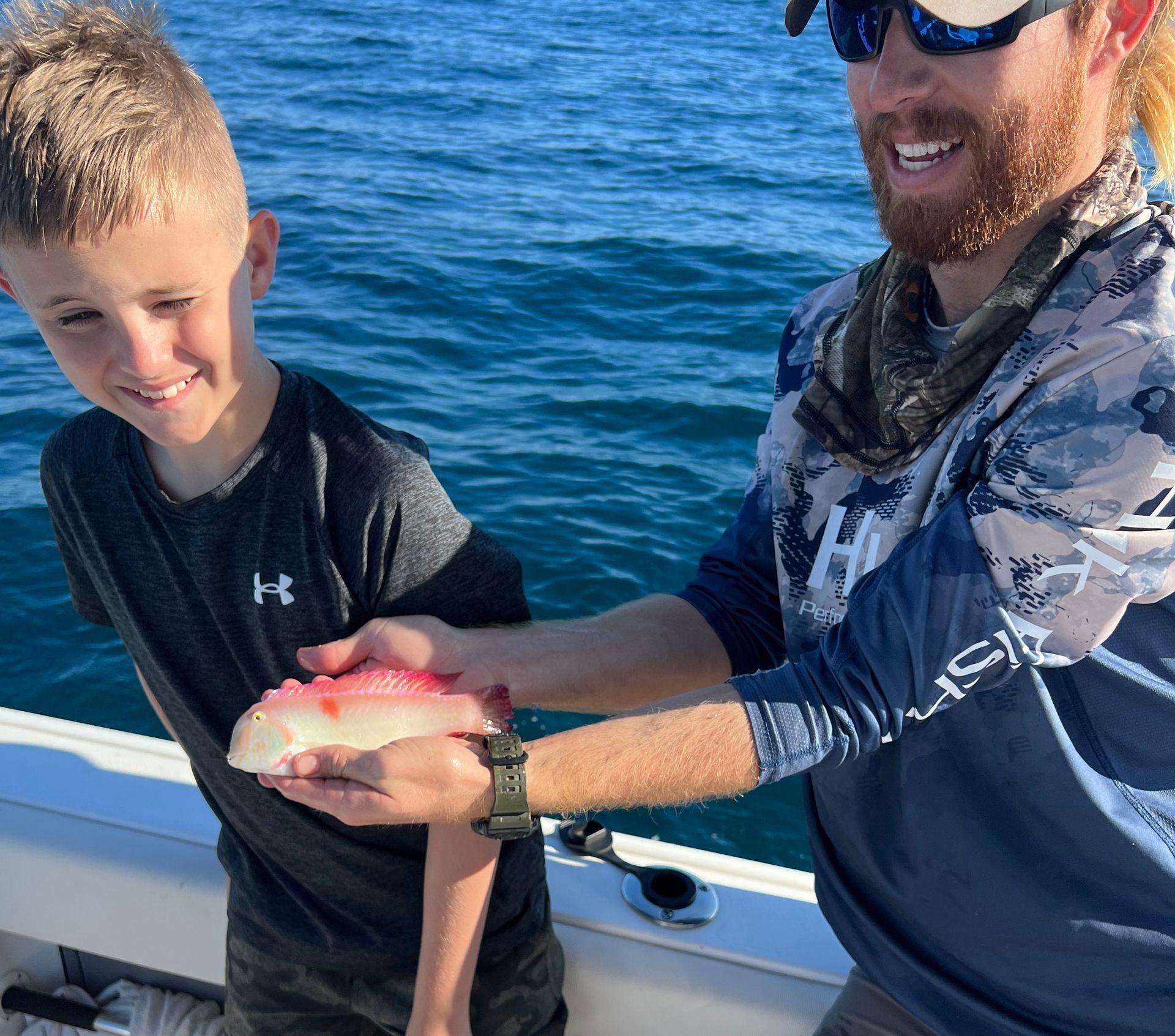 A man is giving a fish to a young boy on a boat.