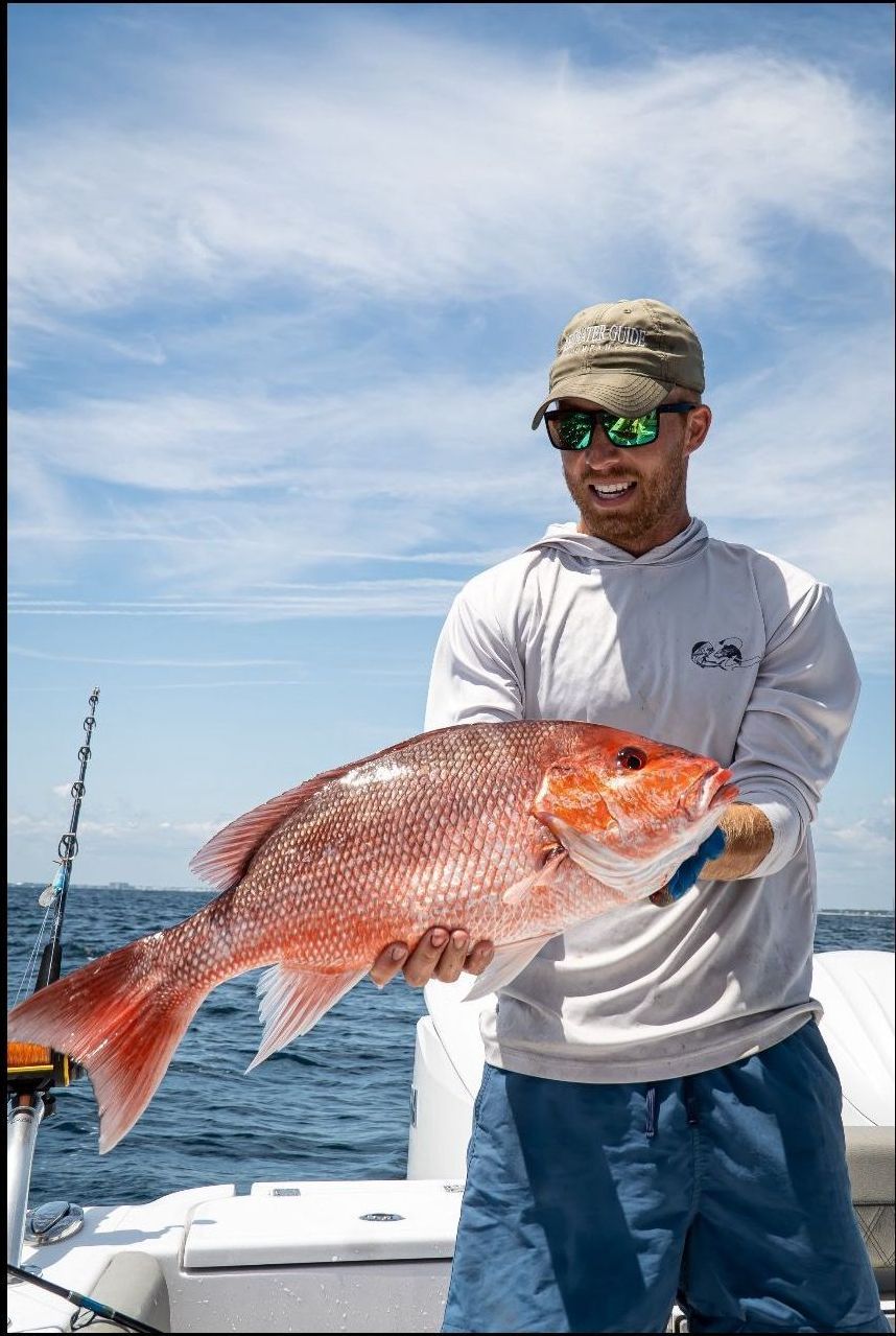 A man is holding a large red fish on a boat.