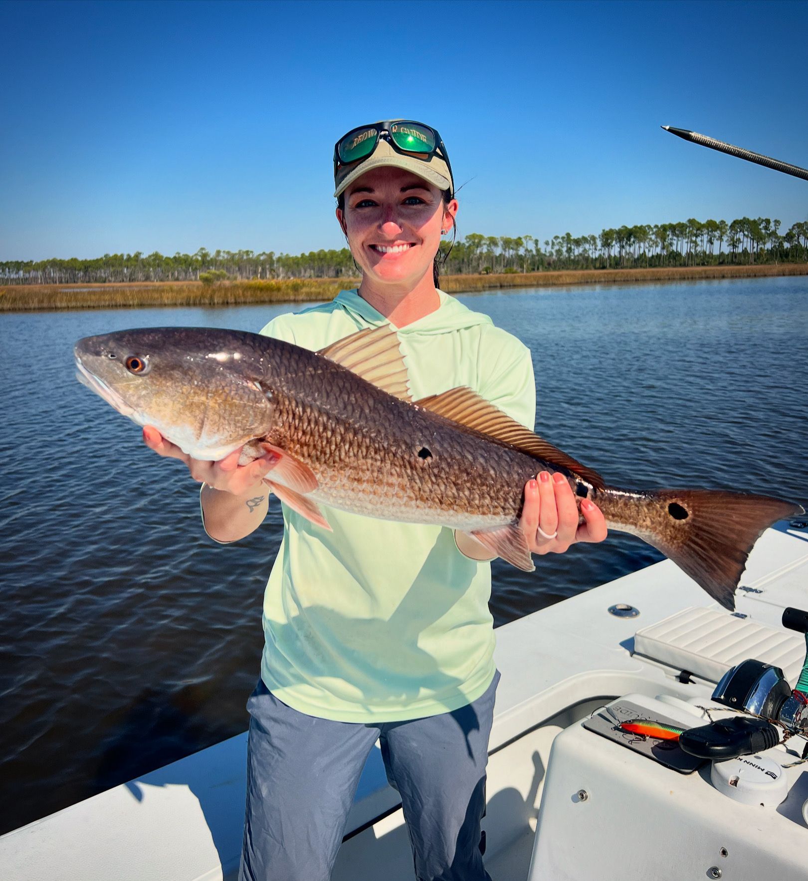 A woman is holding a large fish on a boat