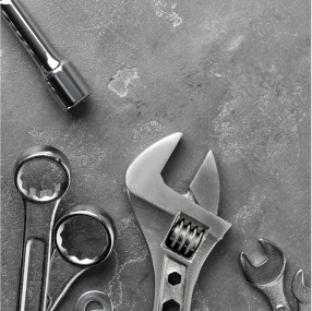 Various metal tools, including wrenches and a socket wrench, arranged on a textured gray surface. | RX Automotive