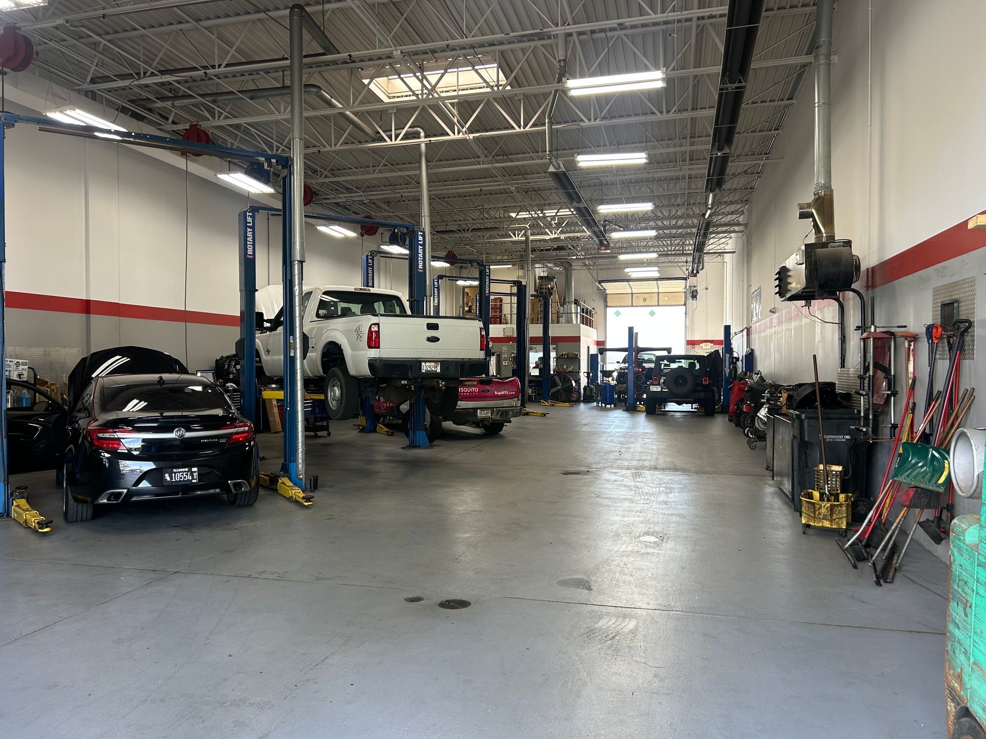 Auto repair shop, multiple cars on lifts, tools and equipment along walls. | RX Automotive