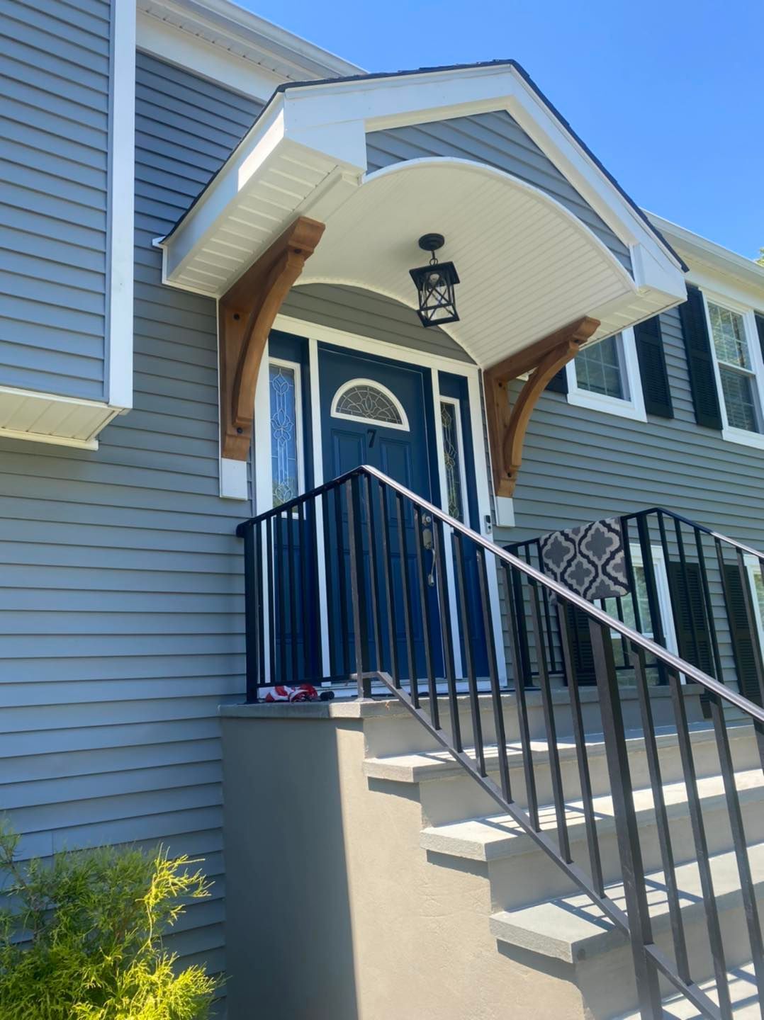 The front of a house with a blue door and stairs leading up to it.