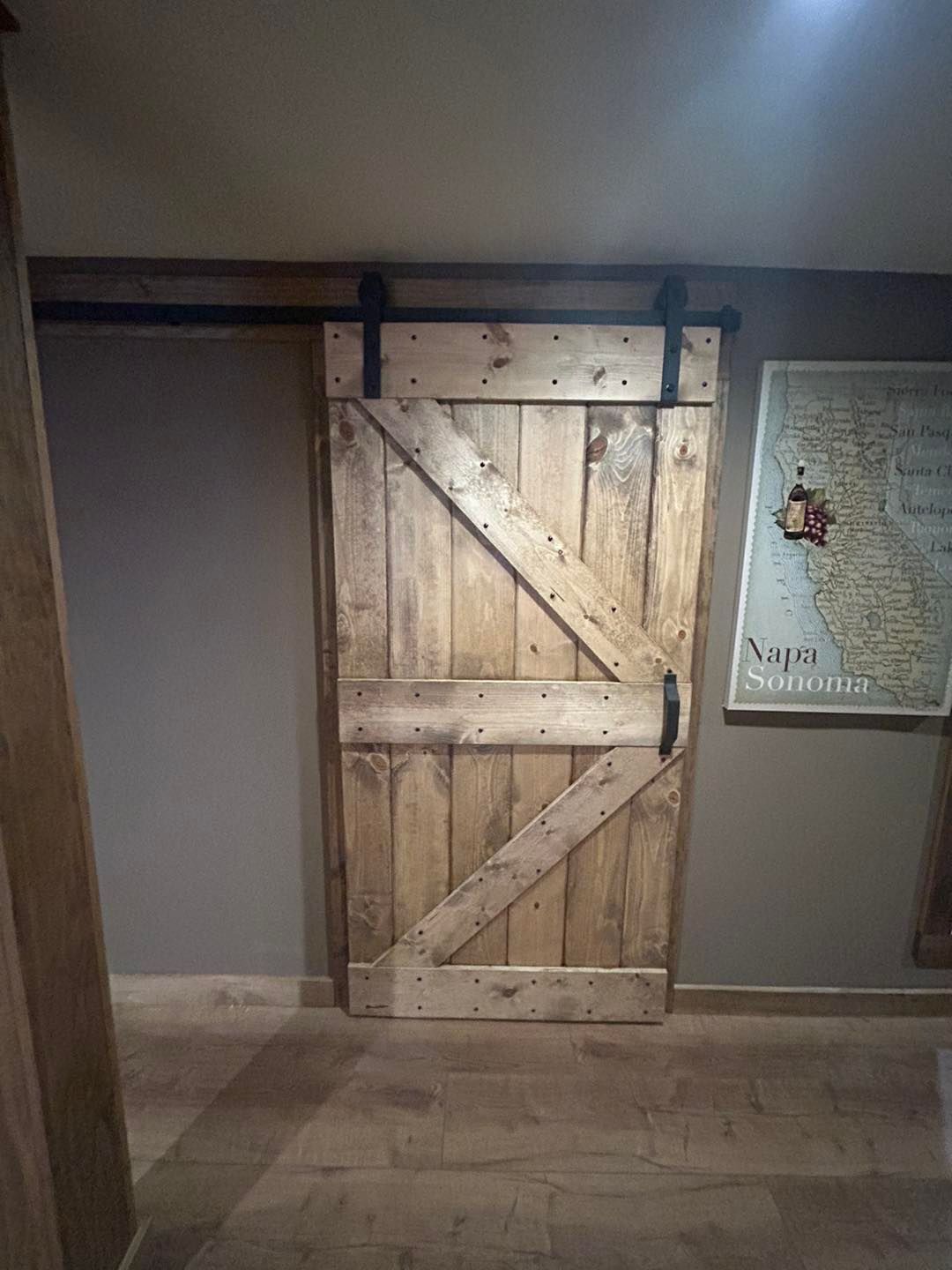 A wooden sliding barn door is hanging on a wall in a hallway.