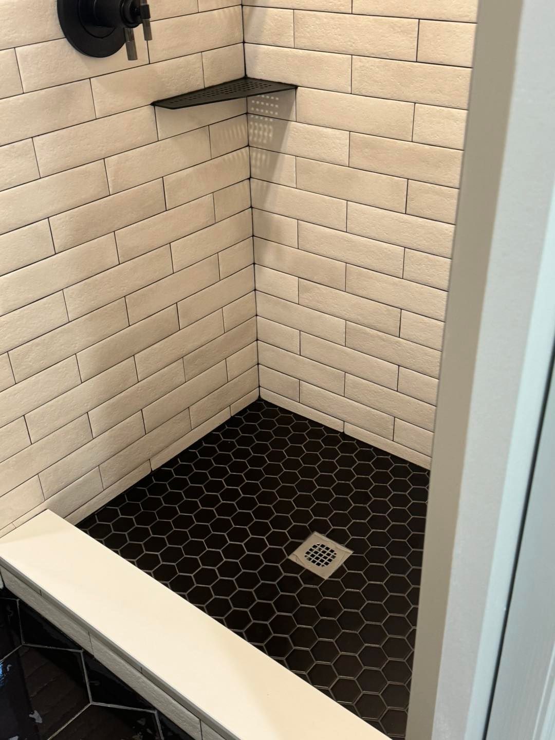 A shower with white brick walls and a black tile floor