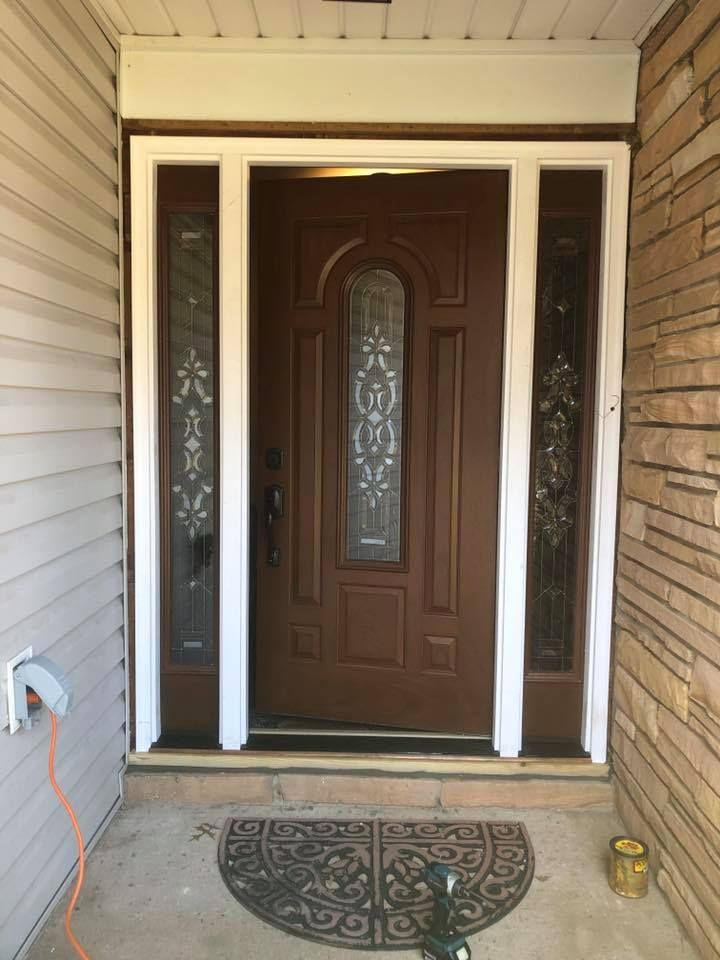 A brown front door with a white trim and a stained glass window.