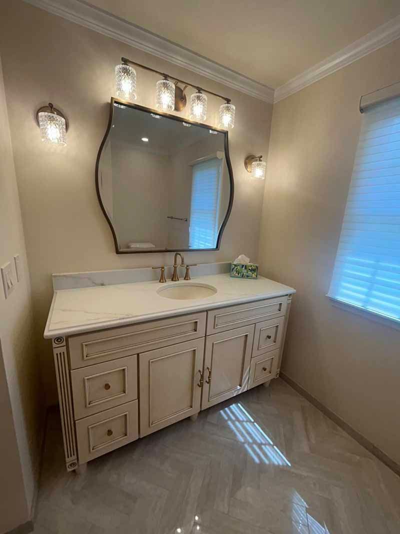 A bathroom with a sink , mirror and window.