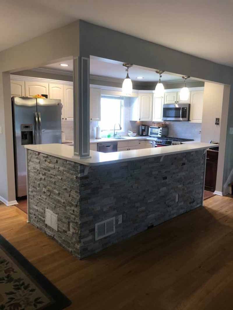 A kitchen with a stone counter top and a refrigerator.