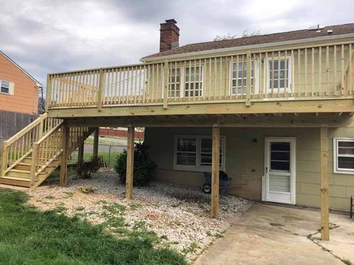 A house with a large wooden deck and stairs.