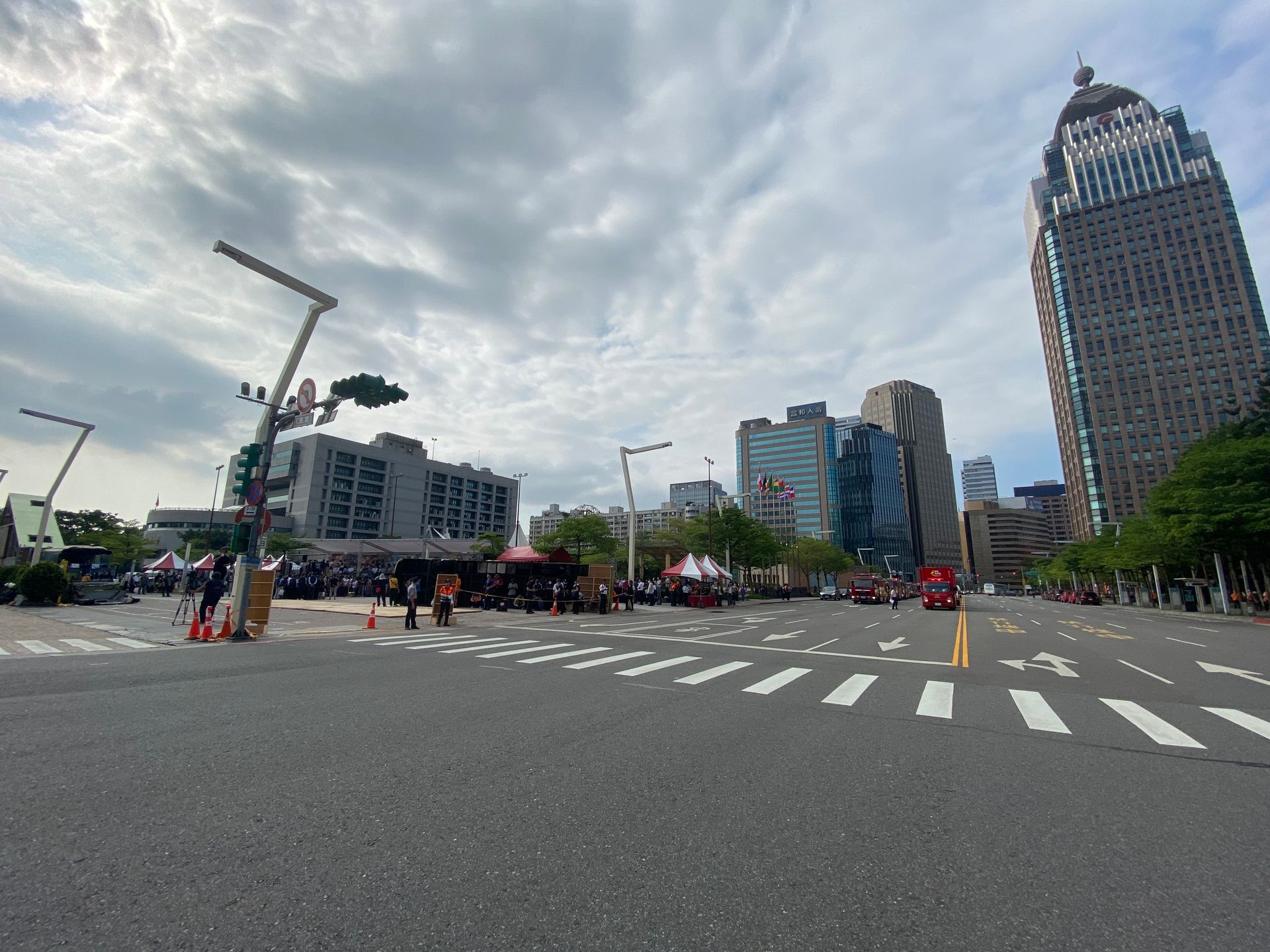 台北的街景，高樓林立，行人穿越道，人群聚集。