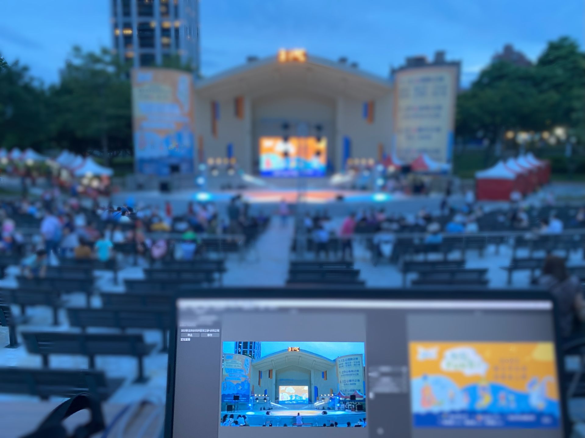 露天劇場舞台擠滿了人，電腦螢幕上顯示著舞台的照片。