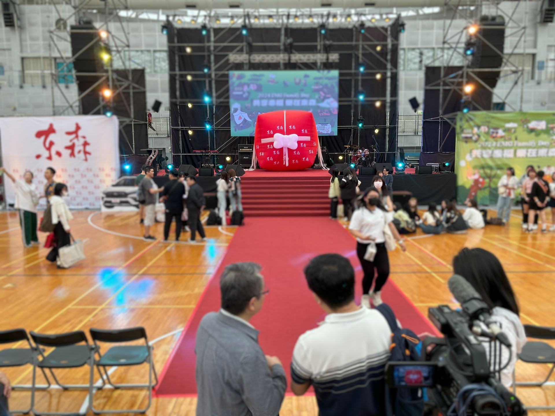 室內場地的舞台活動，有人群、紅毯、大禮、舞台背景。