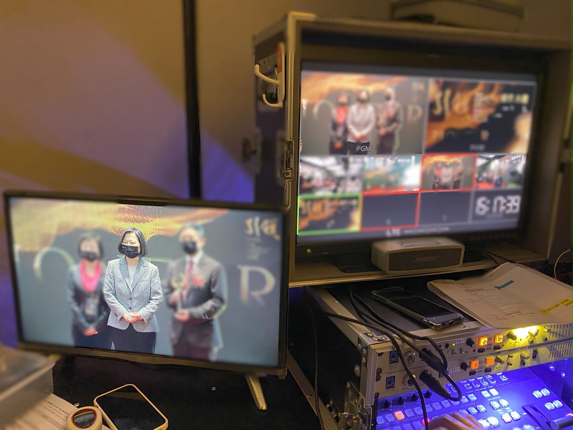 兩個顯示器顯示現場直播：一個女人在講話，另一個是具有不同攝影機角度的多視圖螢幕。