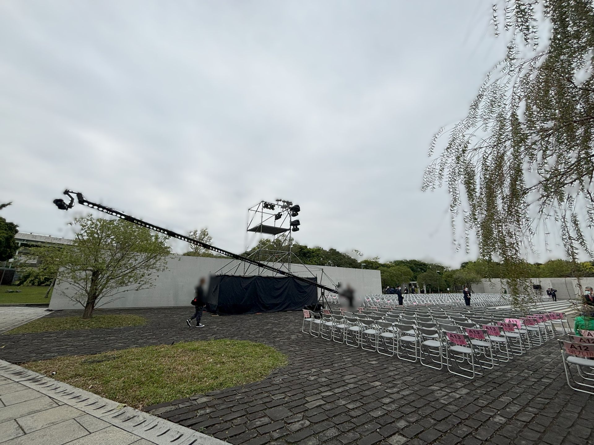 一架黑色起重機，燈光璀璨，為戶外活動搭建。白色座椅擺放整齊，可供就座。