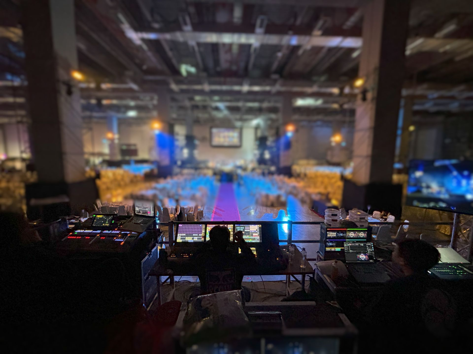 人們在控制站工作，俯瞰著一個大型活動場地。舞台在背景。