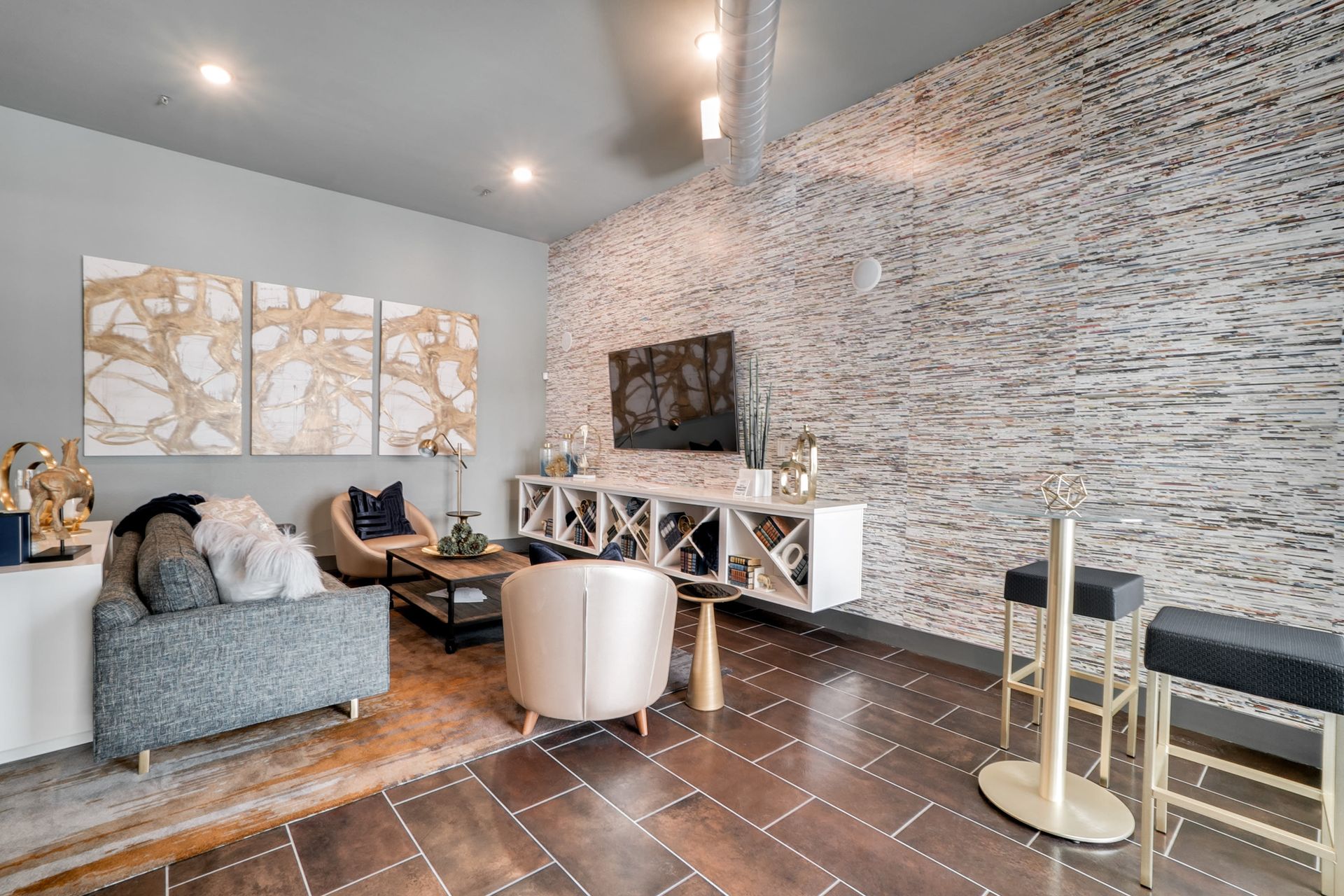 Cozy community lounge with sofa, chairs, coffee table, TV, and a stone accent wall.