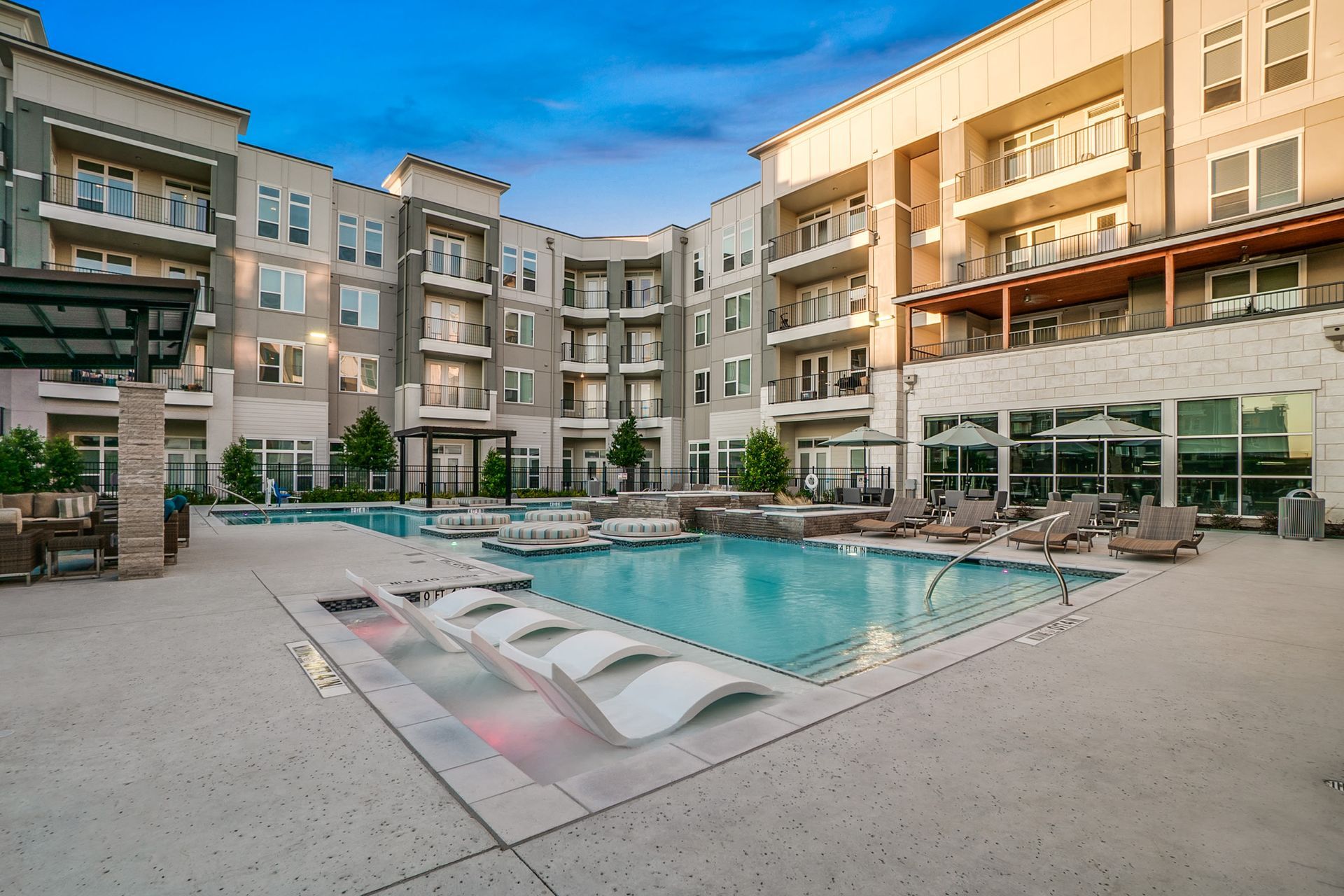 Outdoor pool area with lounge chairs and the surrounding apartment buildings.