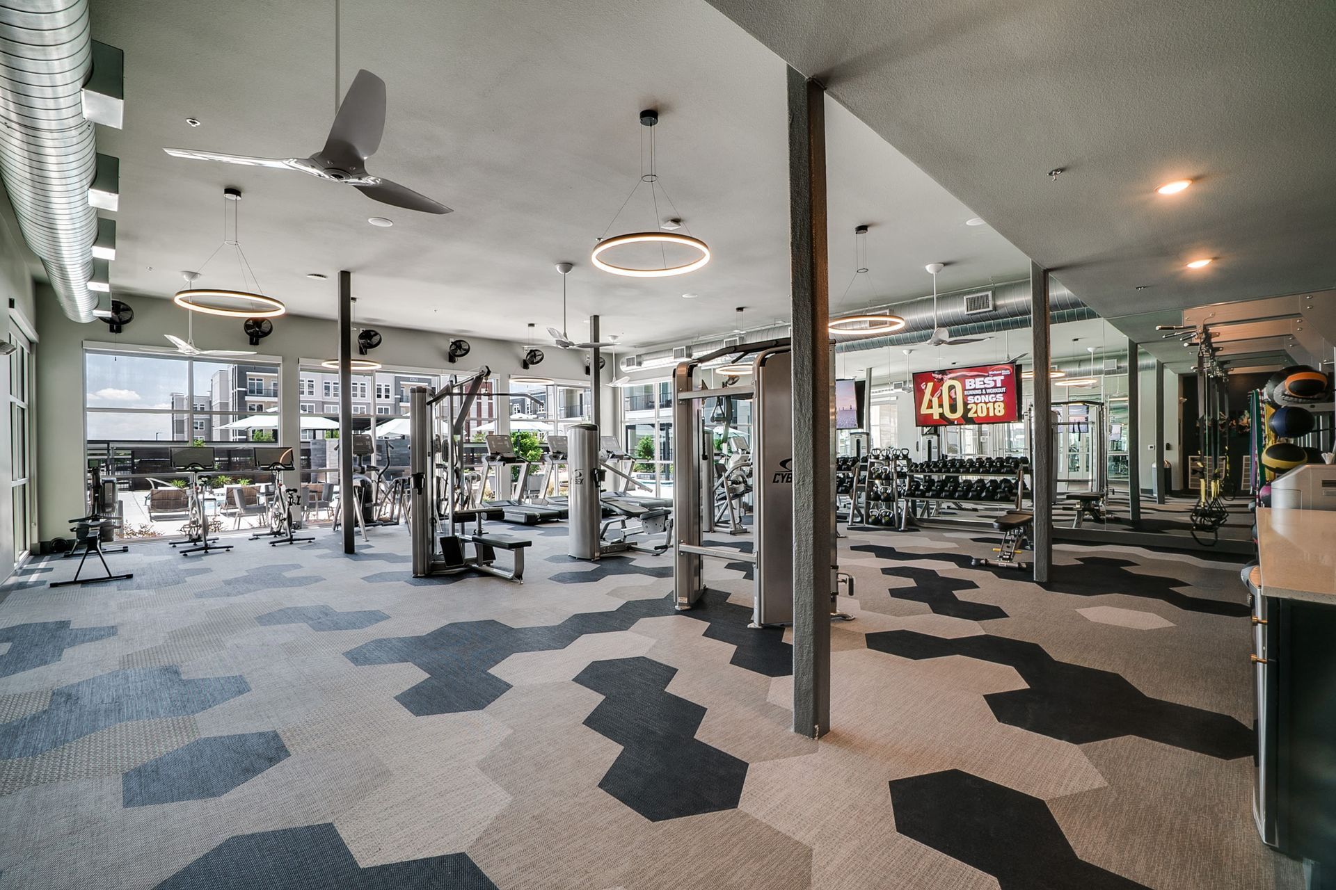 Bright on-site apartment community gym with cardio machines and free weights.