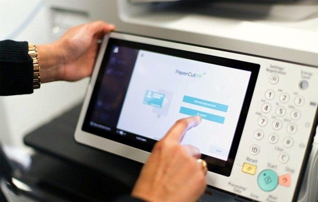 Office employee using a multifunction printer with secure print release enabled.