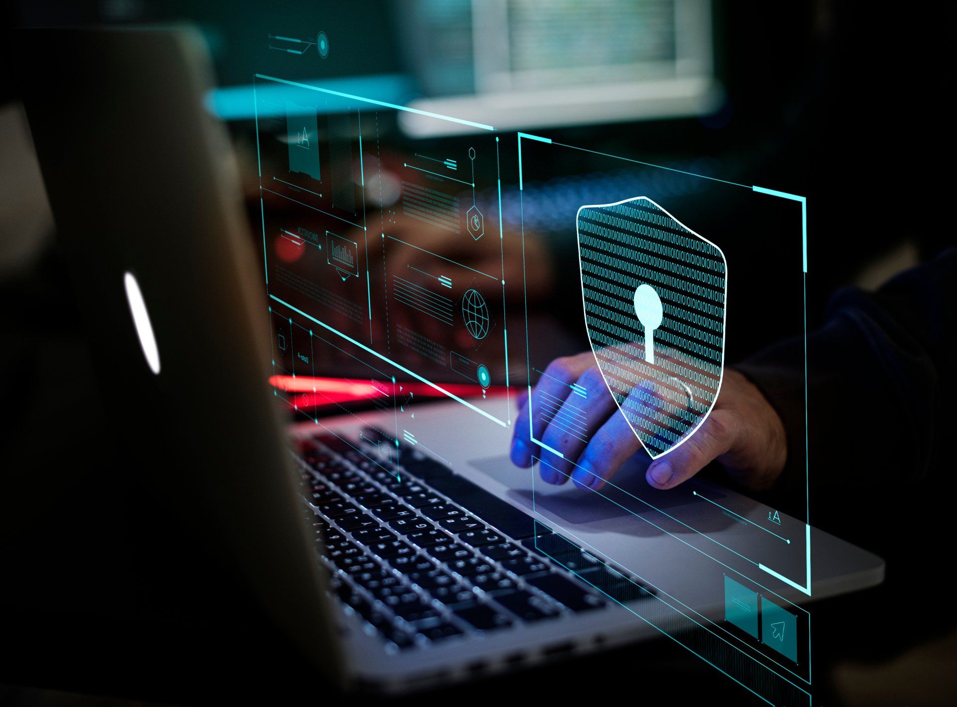 A person is typing on a laptop computer with a shield on the screen.