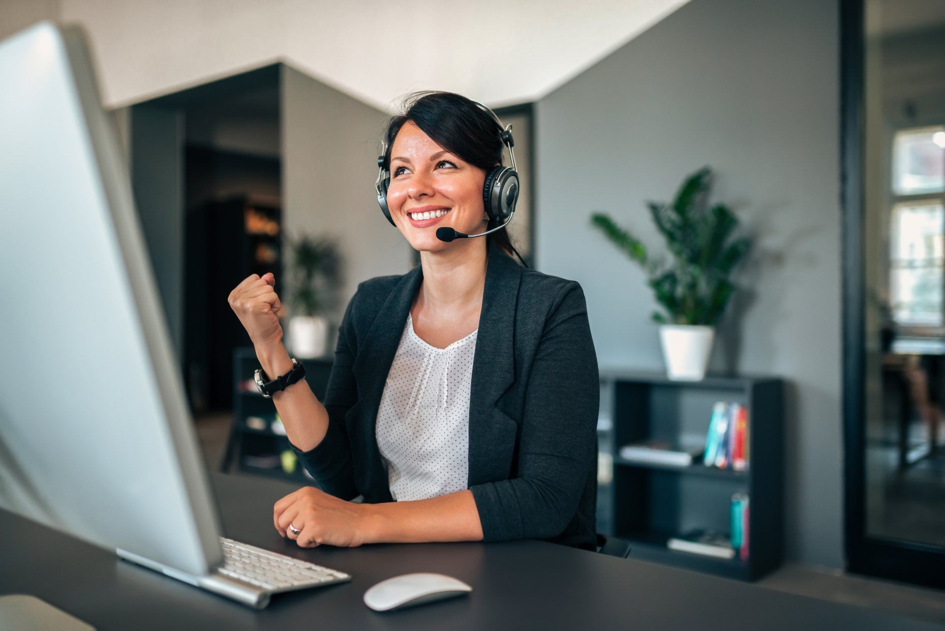 A woman wearing a headset is sitting in front of a computer.