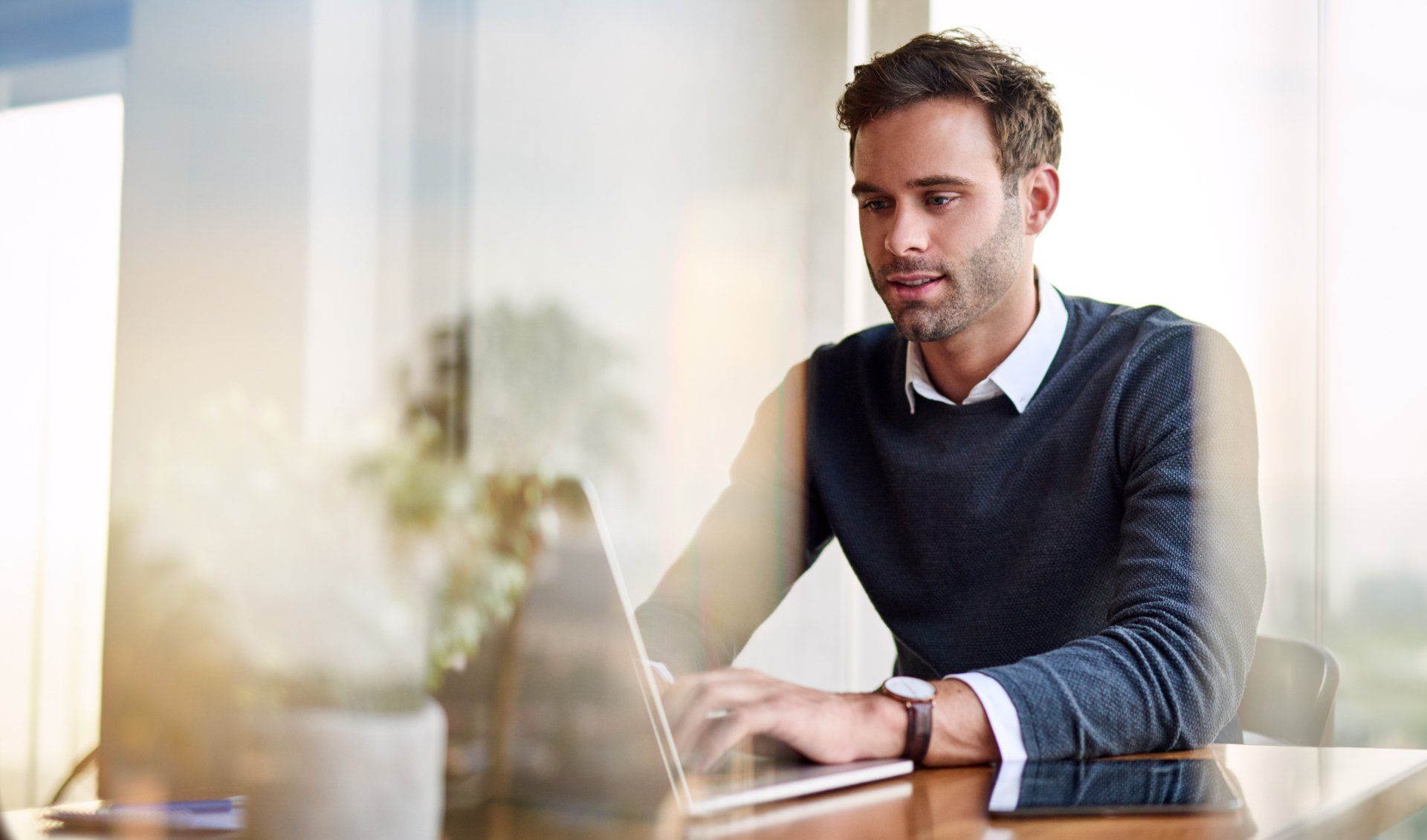 A man is sitting at a desk using a laptop computer.