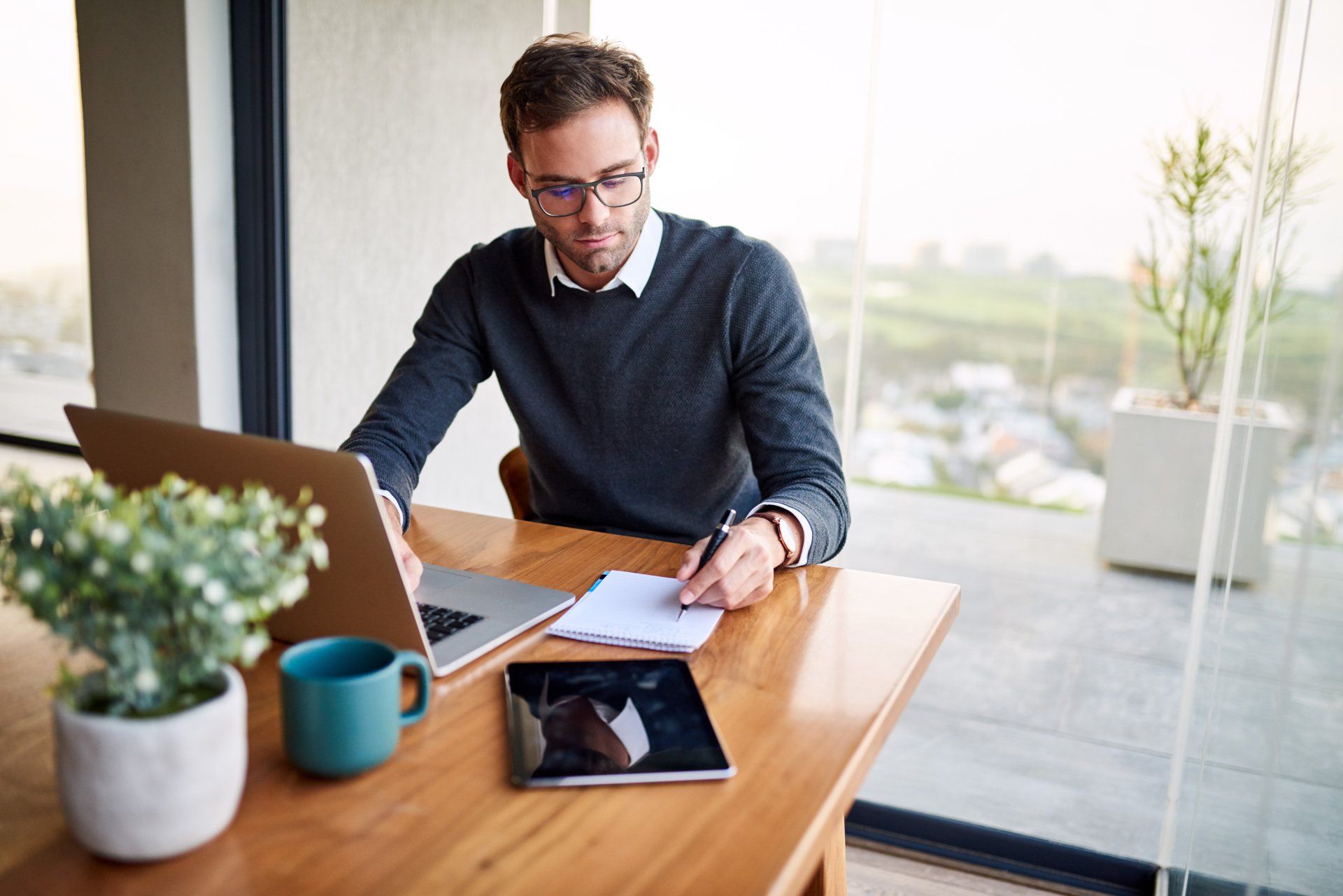A man is sitting at a table using a laptop computer.