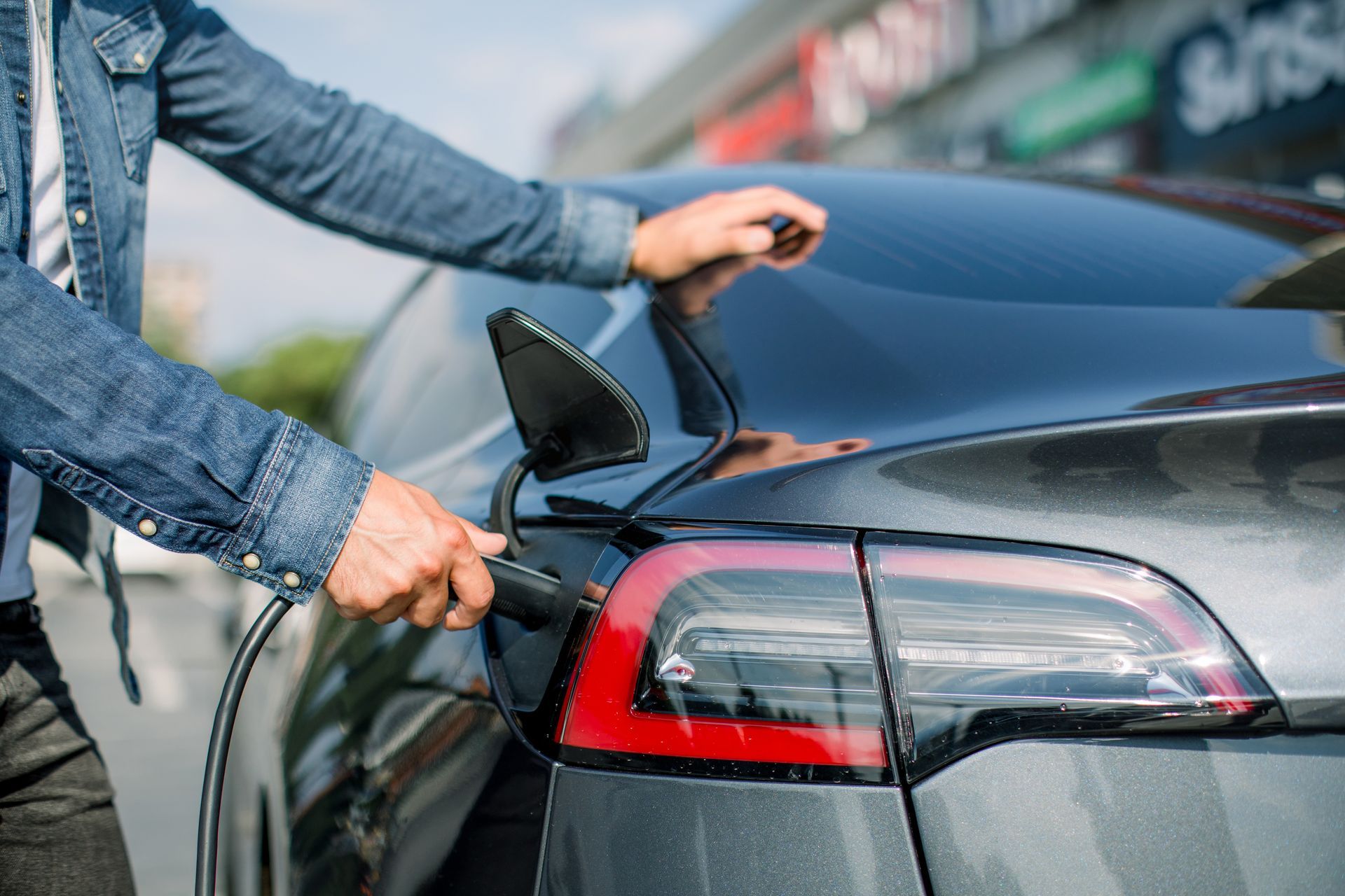 A man is charging an electric car on a city street.