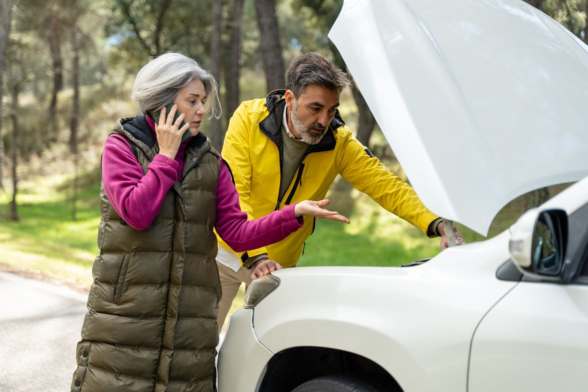 A senior couple is having car trouble on the road and is calling for assistance. A senior couple is having car trouble on the road and is calling for assistance.
