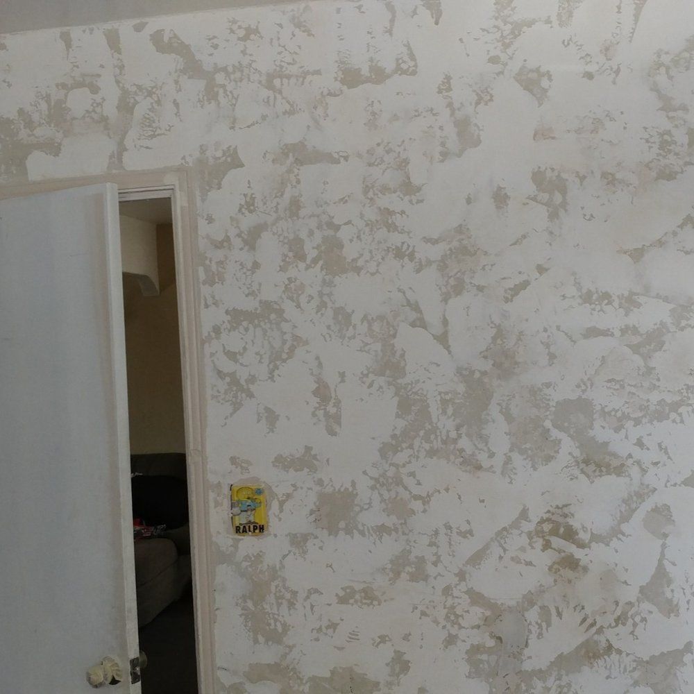 Textured wall with doorframe on left. White and light grey swirled pattern.