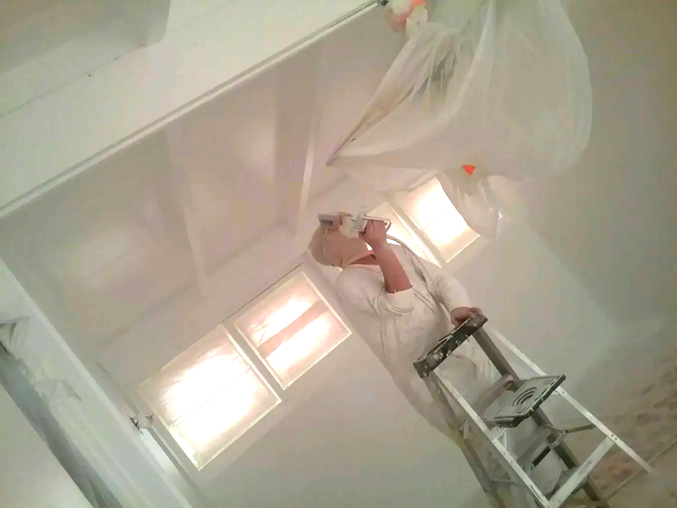 Empty, modern living space with dark wood floors, light gray walls, and open kitchen.