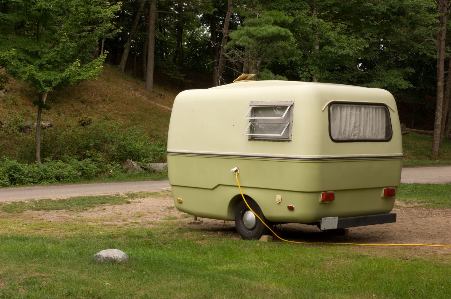 A blue portable toilet is sitting in the middle of a grassy field.