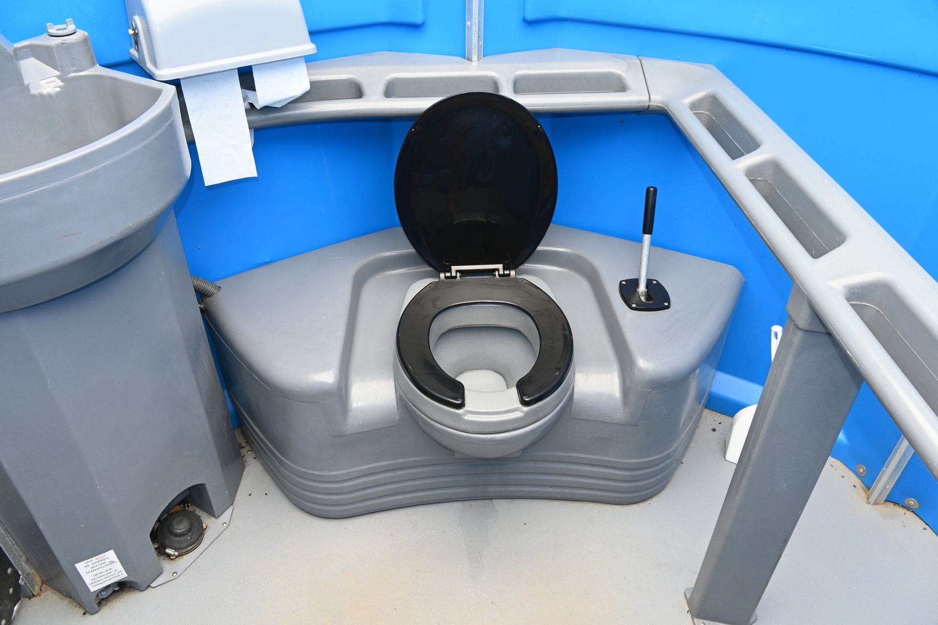 A blue portable toilet is sitting in the middle of a grassy field. A blue portable toilet is sitting in the middle of a grassy field.