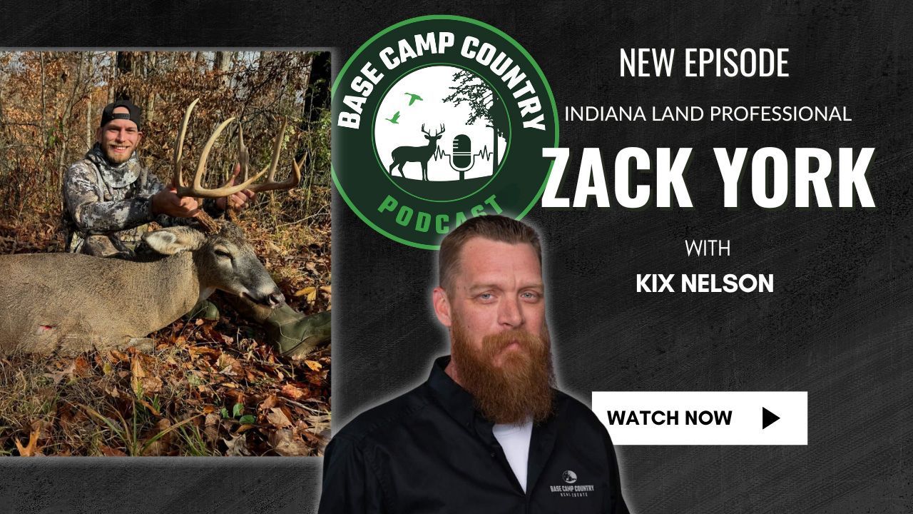 A man with a beard is standing in front of a picture of a deer ..