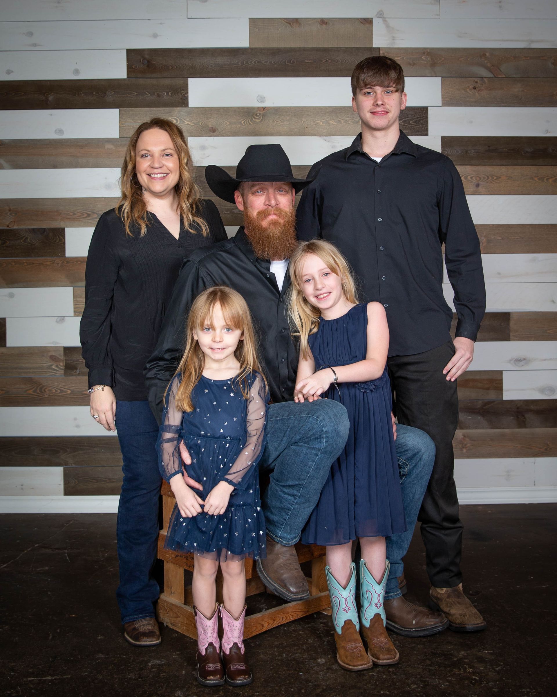 A family posing for a picture in front of a wooden wall.