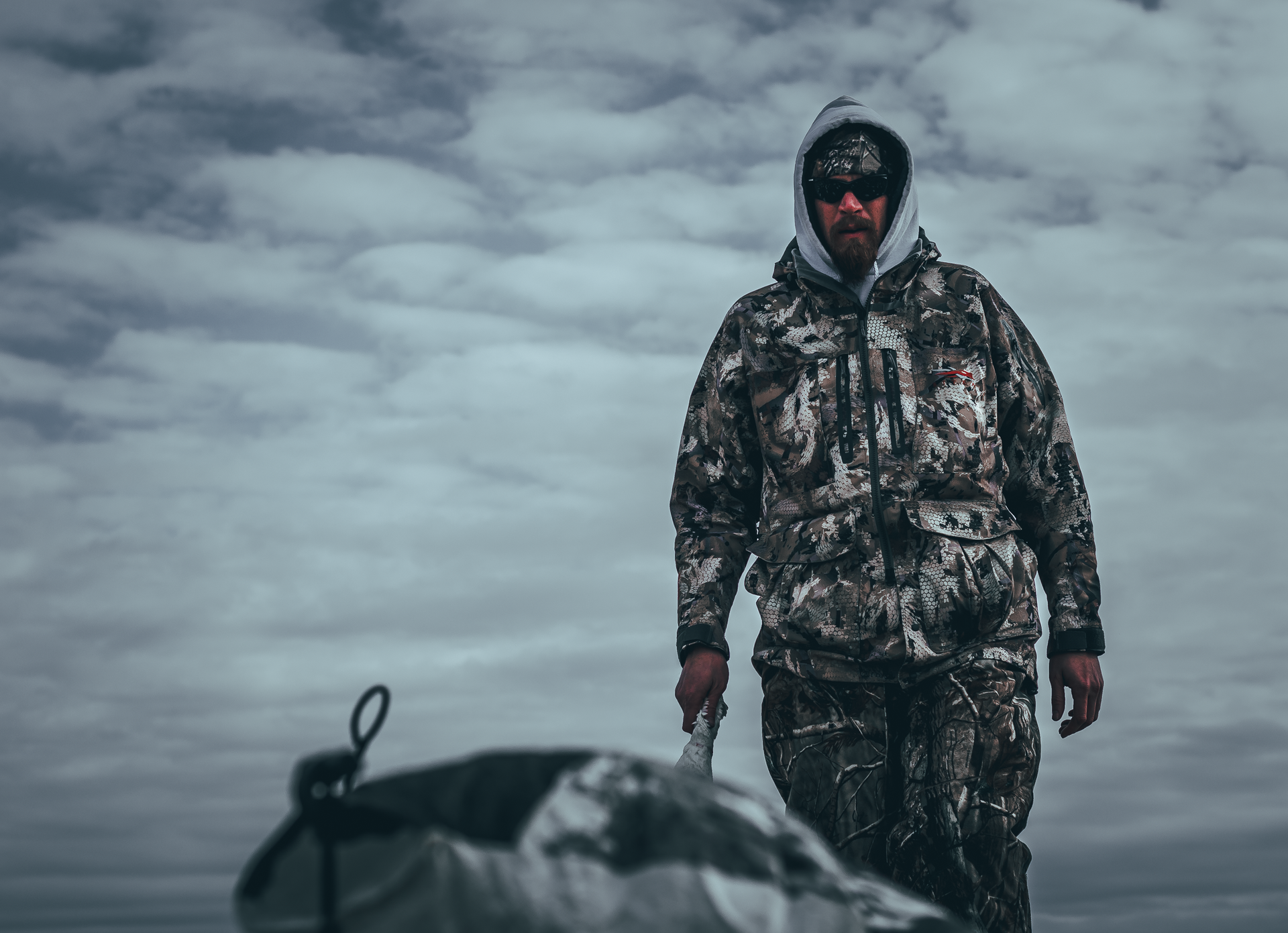 A man in a camouflage jacket is walking in the snow.