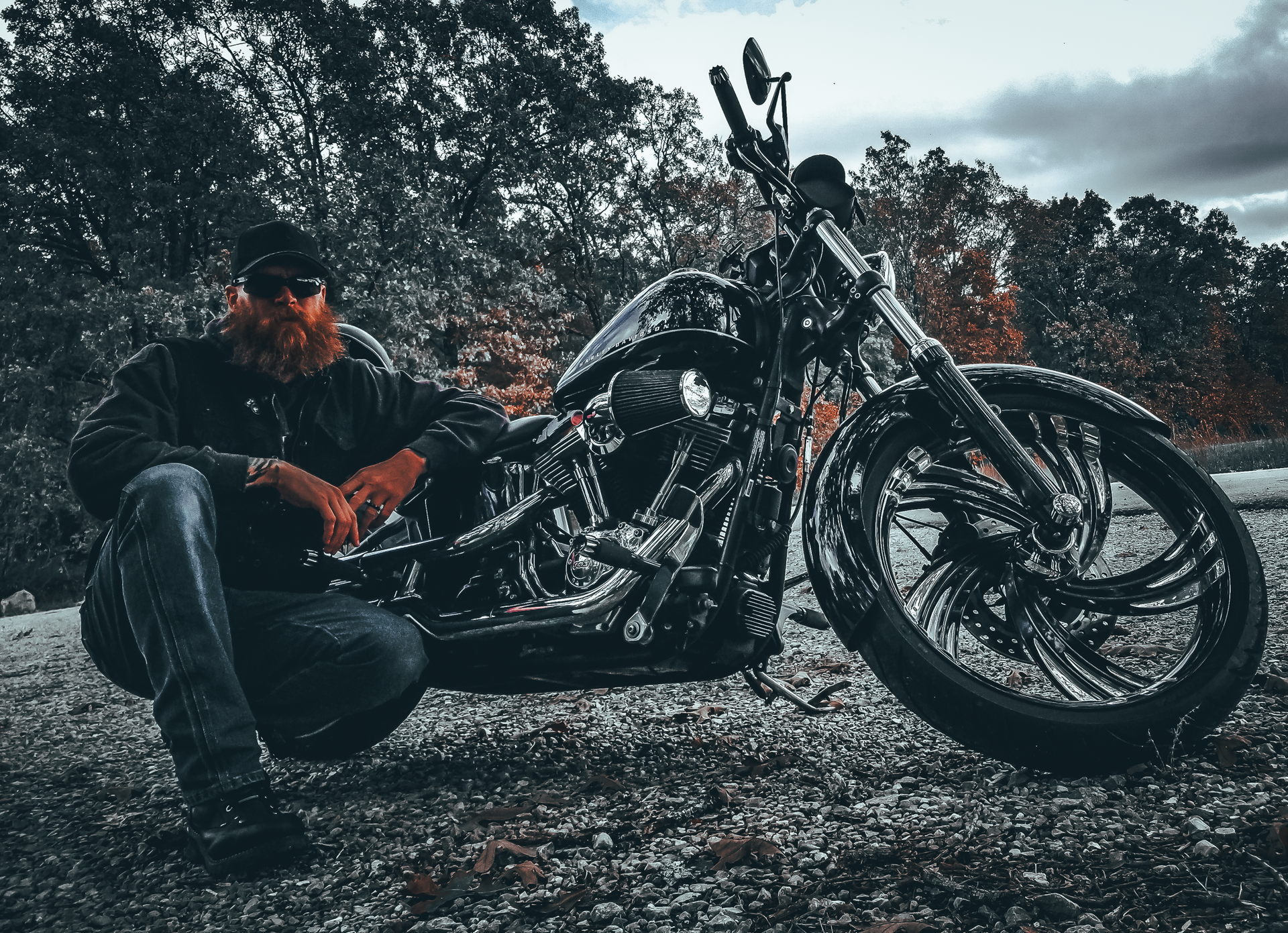 A man is kneeling down next to a motorcycle.