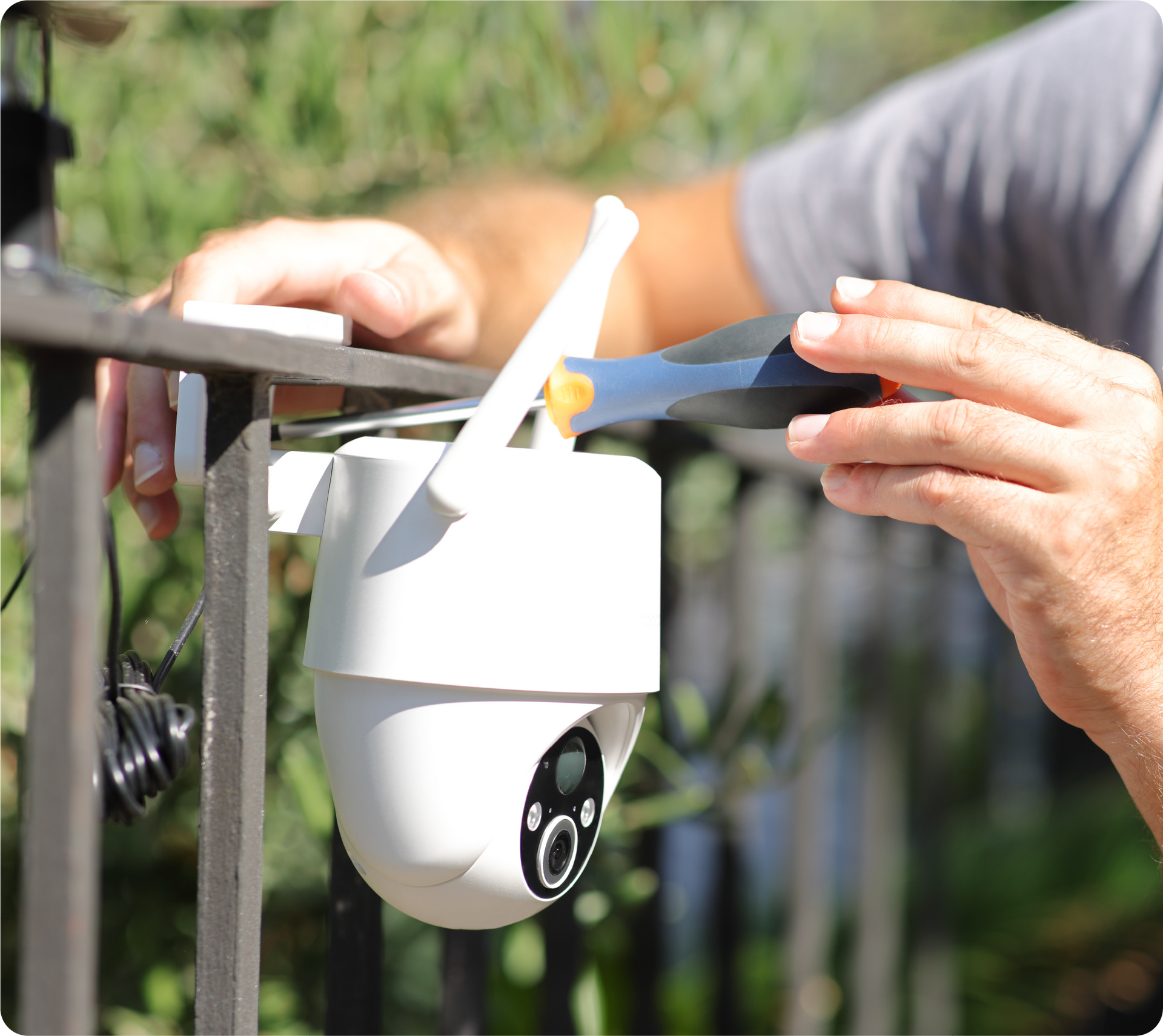 A person is installing a security camera on a fence