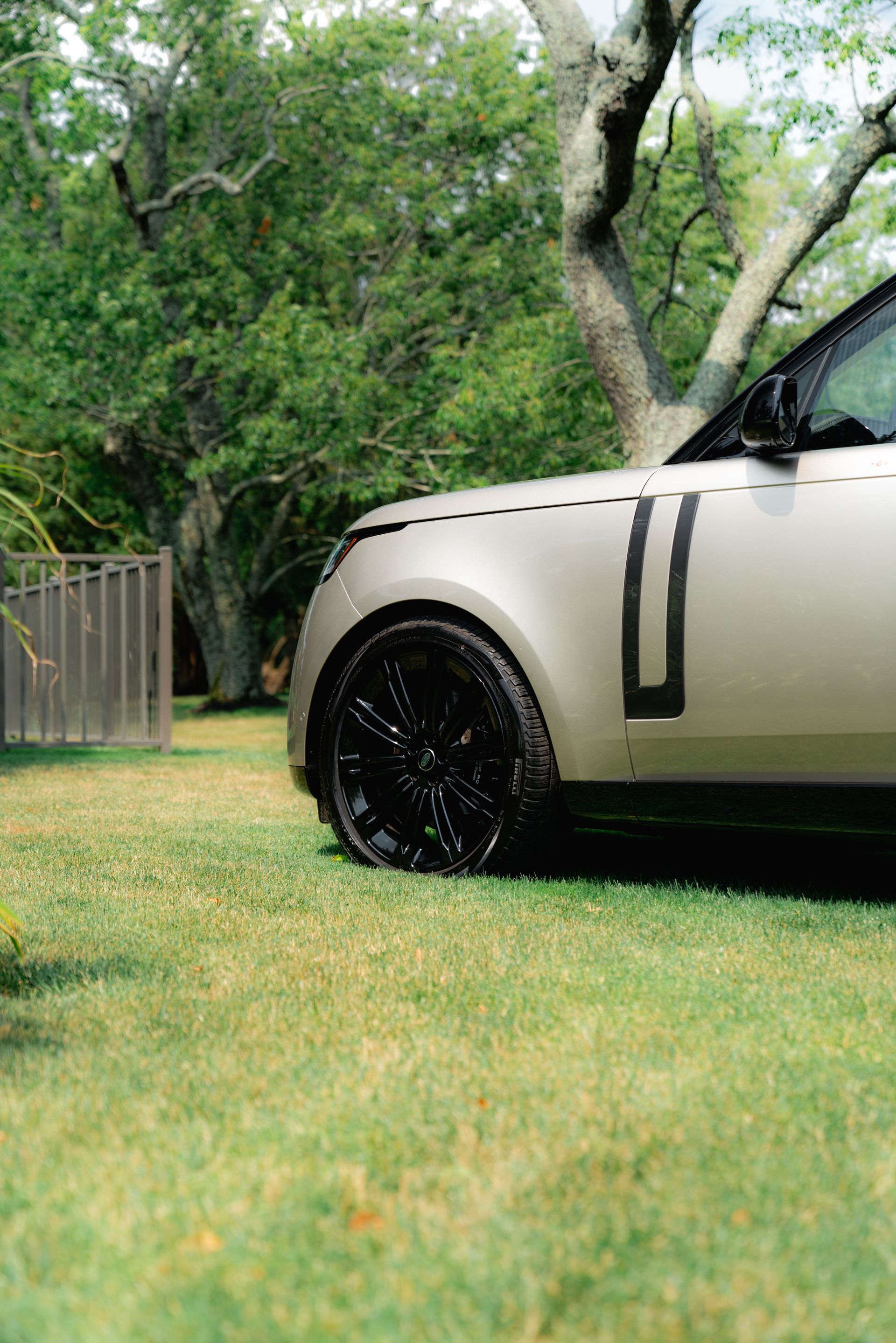 A range rover is parked in the grass in a backyard.