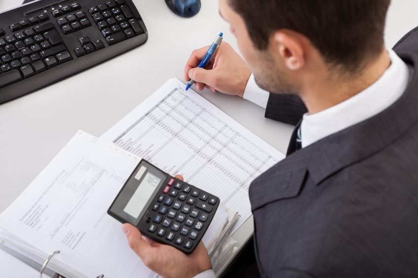 A man is using a calculator and writing on a piece of paper