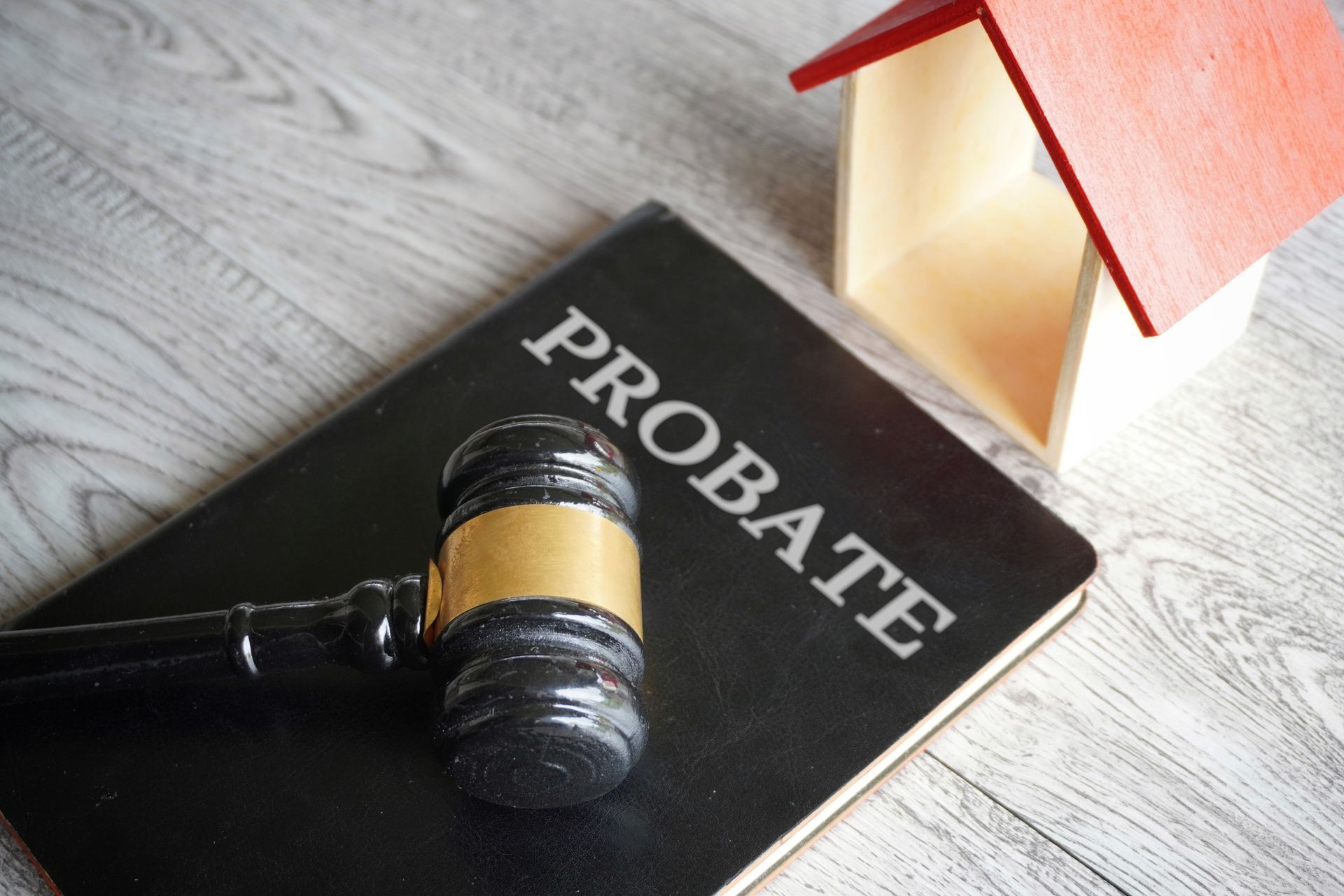 Toy house next to a wooden gavel with bold text “PROBATE” symbolizing estate law matters.