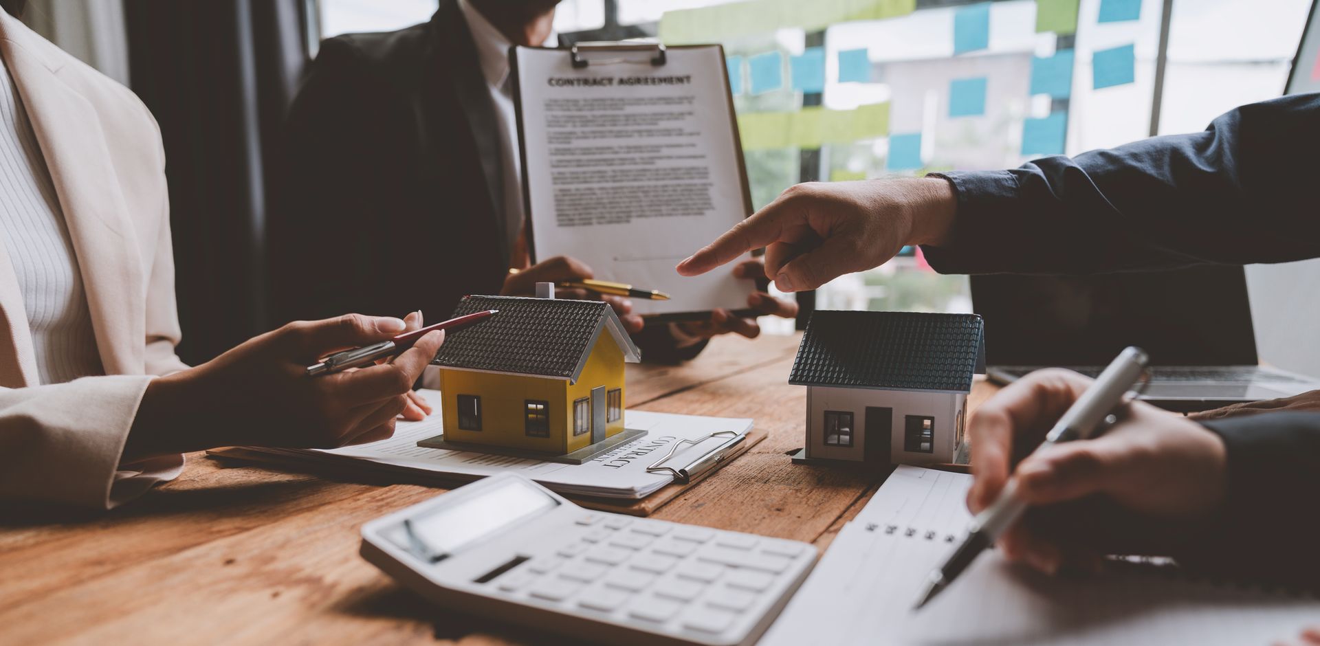 People reviewing contracts and model houses during a real estate meeting.