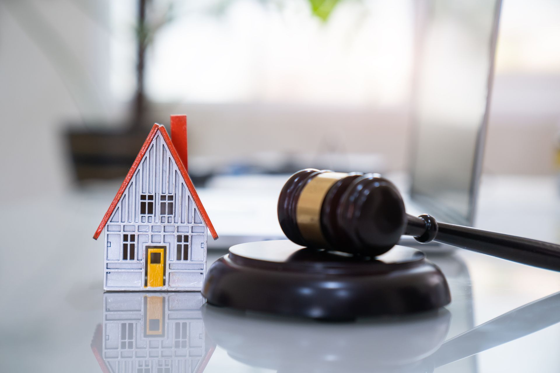 Estate attorney legal decision symbolized by house model beside judge's gavel on glass table