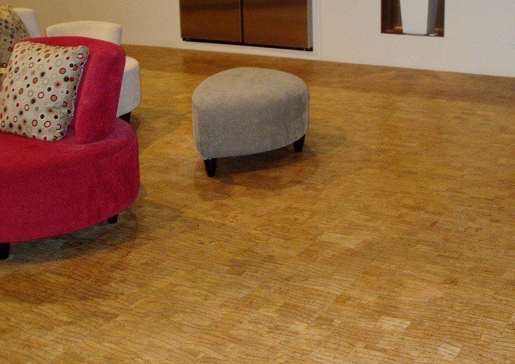 A living room with a pink chair and a grey ottoman