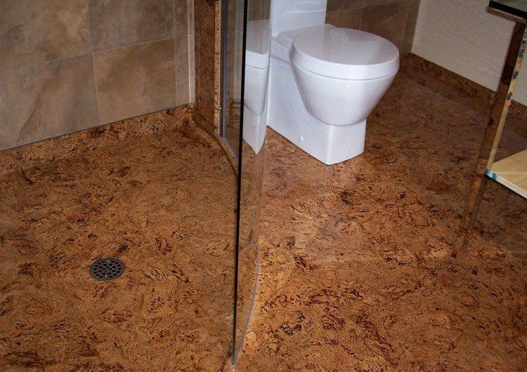 A toilet in a bathroom with a cork floor